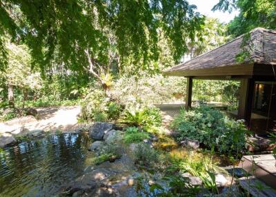 A serene garden with a small pond, lush greenery, and a gazebo.