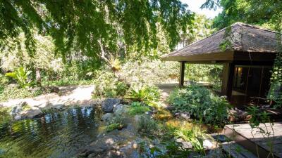 A serene garden with a small pond, lush greenery, and a gazebo.