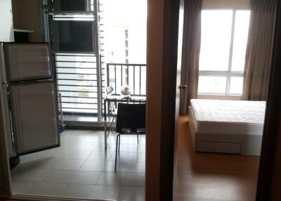 View of studio apartment with open fridge, table, balcony, and bed