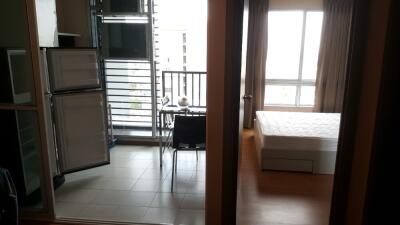 View of studio apartment with open fridge, table, balcony, and bed