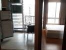 View of studio apartment with open fridge, table, balcony, and bed