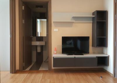 Modern living area with a wall-mounted TV and shelves next to a bathroom