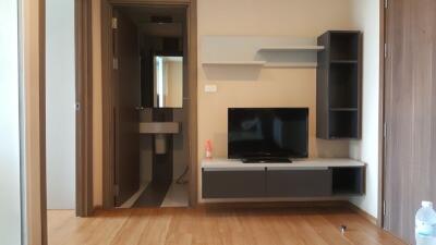 Modern living area with a wall-mounted TV and shelves next to a bathroom