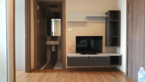 Modern living area with a wall-mounted TV and shelves next to a bathroom