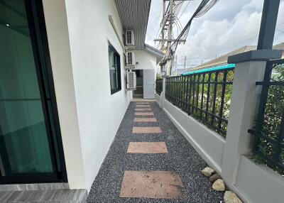Outdoor walkway leading to the backyard with air conditioning units attached to the wall