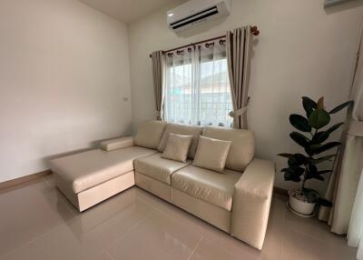 Modern living room with beige sofa, air conditioner, curtains, and indoor plant