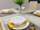 Modern dining table setup with white dishes and gold flatware