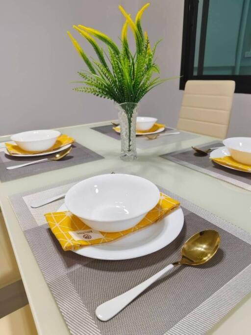 Modern dining table setup with white dishes and gold flatware