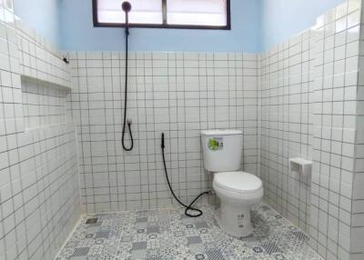 A well-lit bathroom with a toilet and showerhead