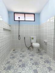 A well-lit bathroom with a toilet and showerhead