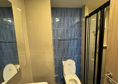 Modern bathroom with blue tiled wall and glass shower enclosure