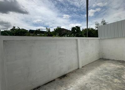 Spacious outdoor area with high wall and a cloudy sky