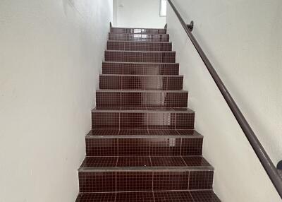 Brown tiled staircase with black handrail