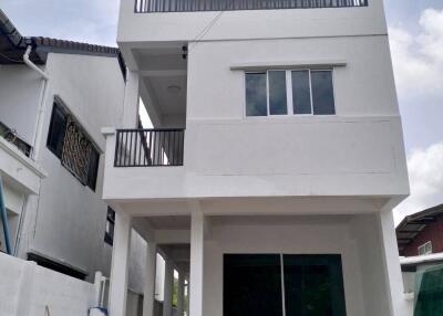 Front view of a two-story white house with a balcony and large windows