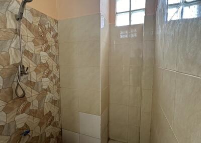 Shower area with beige tiles and a small window