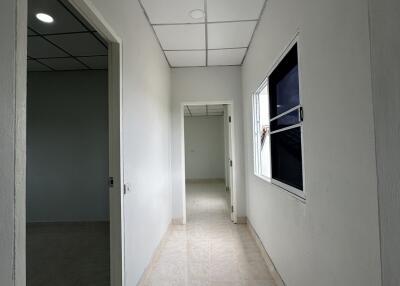 Long hallway with white walls and several rooms