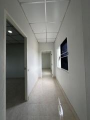 Long hallway with white walls and several rooms