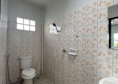 Tiled bathroom with window, shower, and toilet