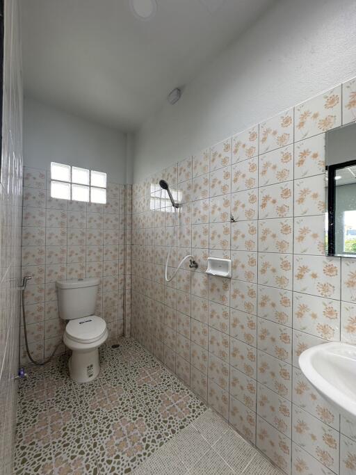 Tiled bathroom with window, shower, and toilet