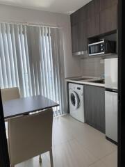 Modern kitchen with dining area, washing machine, microwave, and refrigerator