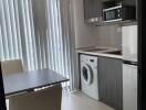 Modern kitchen with dining area, washing machine, microwave, and refrigerator