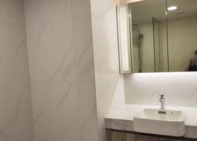 Modern bathroom with white fixtures and marble-tiled walls