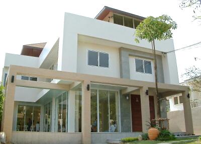 Modern two-story house exterior with large windows and a garden