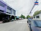 Street view of residential area with building, cars, and motorcycles