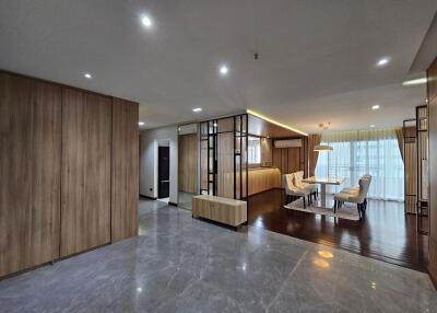 Spacious modern living and dining area with wooden and marble flooring, recessed lighting, and large windows