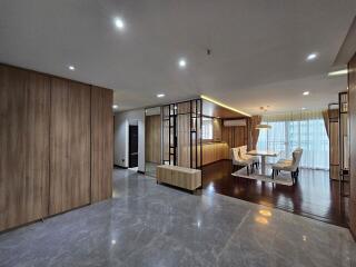 Spacious modern living and dining area with wooden and marble flooring, recessed lighting, and large windows