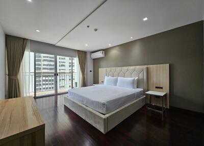 Spacious modern bedroom with a large bed, wooden flooring, and a balcony view