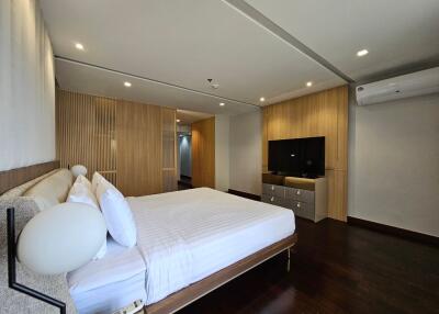 Modern bedroom with wooden paneling, large bed, and wall-mounted TV