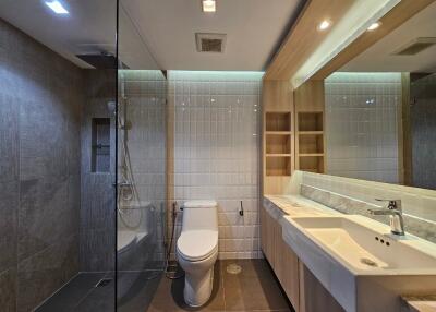 Modern bathroom with glass shower, toilet, and large mirror