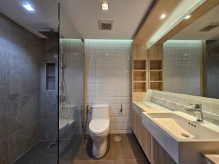 Modern bathroom with glass shower, toilet, and large mirror