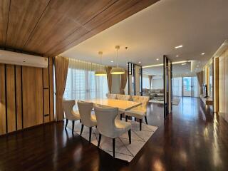 Modern dining area with table and chairs, adjacent to living room with large windows