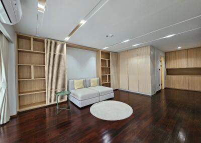 Spacious living room with built-in wooden bookshelves, sofa, and hardwood floors