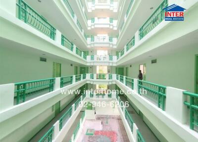 Interior of a multi-storey apartment building with green railings and a central atrium