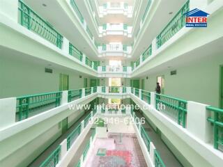 Interior of a multi-storey apartment building with green railings and a central atrium