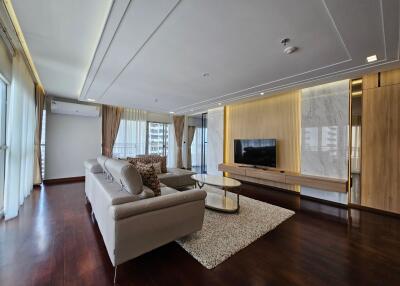 Modern living room with large sofa, flat screen TV, and floor-to-ceiling windows
