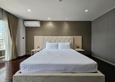 Modern bedroom with a large bed, bedside tables, air conditioning, and large window