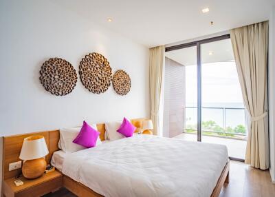 Bright modern bedroom with a large bed, decorative wall art, and a balcony view