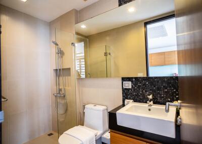 Modern bathroom with glass shower, toilet, and vanity with large mirror