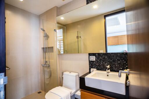 Modern bathroom with glass shower, toilet, and vanity with large mirror