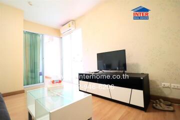 Modern living room with a TV, glass coffee table, and sliding door