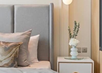 Modern bedroom with a gray upholstered headboard and a bedside table with a lamp and floral decoration