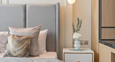 Modern bedroom with a gray upholstered headboard and a bedside table with a lamp and floral decoration