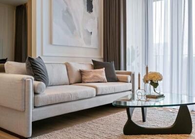 Elegant living room with a light-colored sofa, glass coffee table, and large window