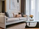 Elegant living room with a light-colored sofa, glass coffee table, and large window