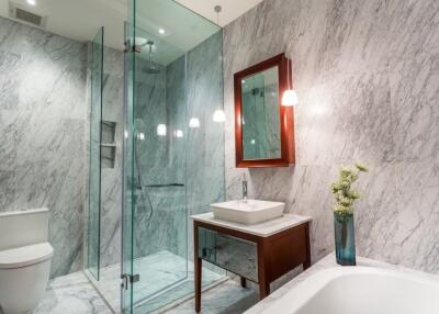Modern bathroom with marble walls, glass shower, and vanity