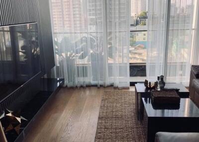 Modern living room with floor-to-ceiling windows, a sleek sectional sofa, wooden floors, and a view of the city.